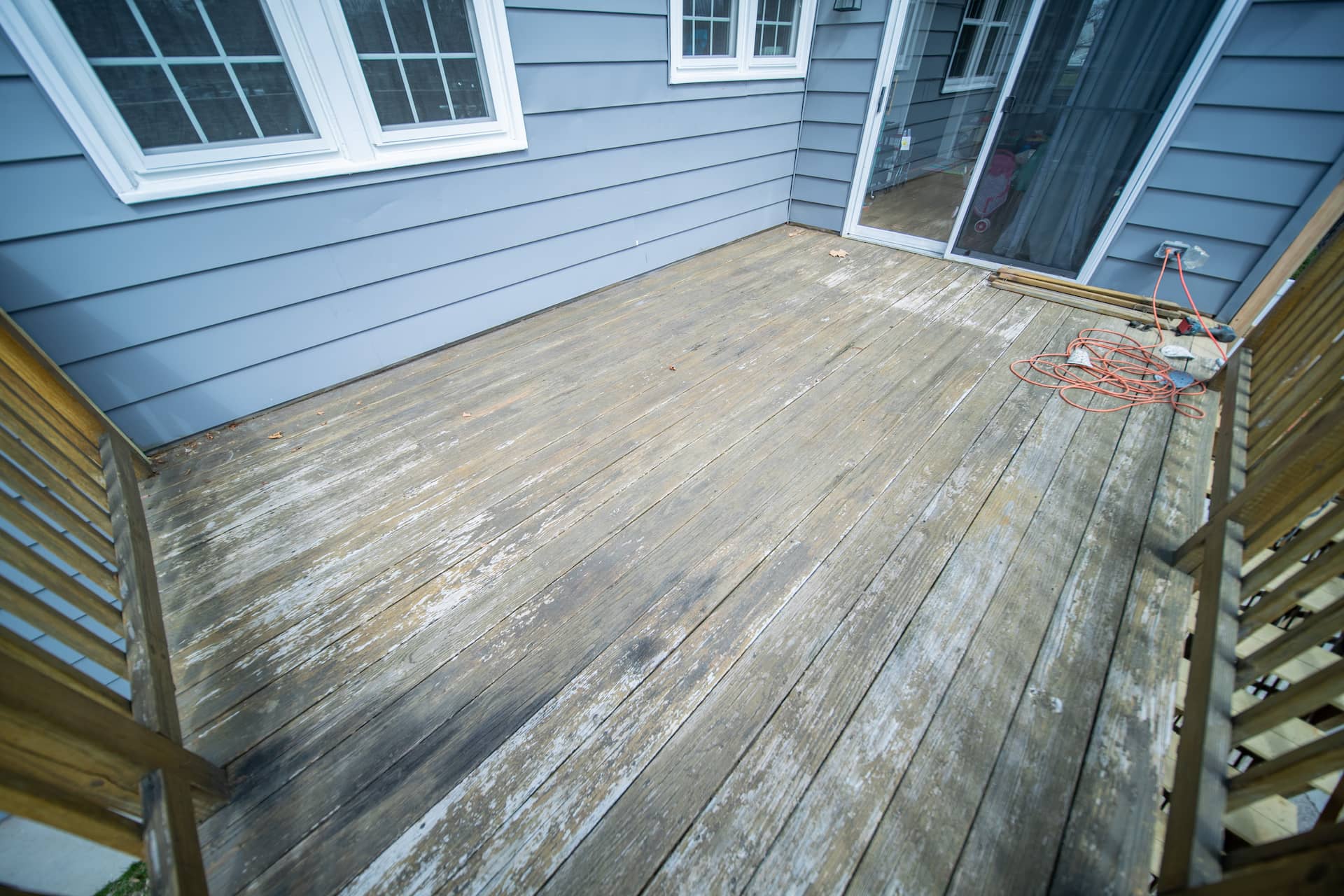Grayed, water-stained wood boards with a failing finish before restoration