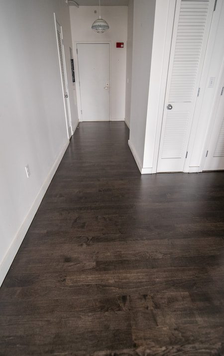 Elegant high-ceiling room with large windows and sleek hardwood floors installed by Weles Hardwood Flooring Company, featuring a contemporary design with natural light enhancing the warm wood tones, ideal for showcasing modern interior design in a spacious setting.