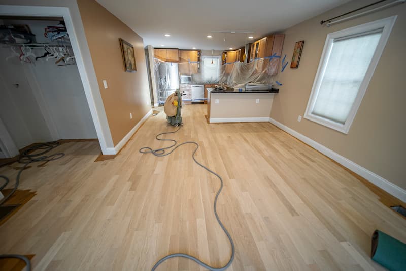 In-progress dustless sanding of light hardwood floors by Weles, highlighting the company’s attention to detail and commitment to maintaining a clean work environment during renovation.