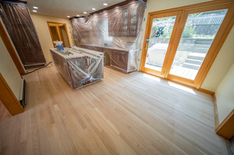 Renovation scene with active sanding equipment on hardwood floors, depicting Weles’ expertise in preparing and refinishing floors in a residential setting.